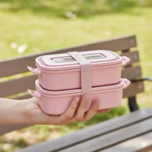 A hand holding the lightweight pink bento lunch box, demonstrating its easy portability and compact size.