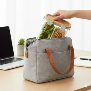 A compact glass bento box lunch box tucked inside a modern insulated tote bag for work commuters.