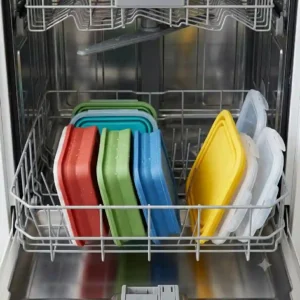 Dishwasher-safe collapsible tupperware loaded flat into the top rack of a dishwasher for easy cleaning.